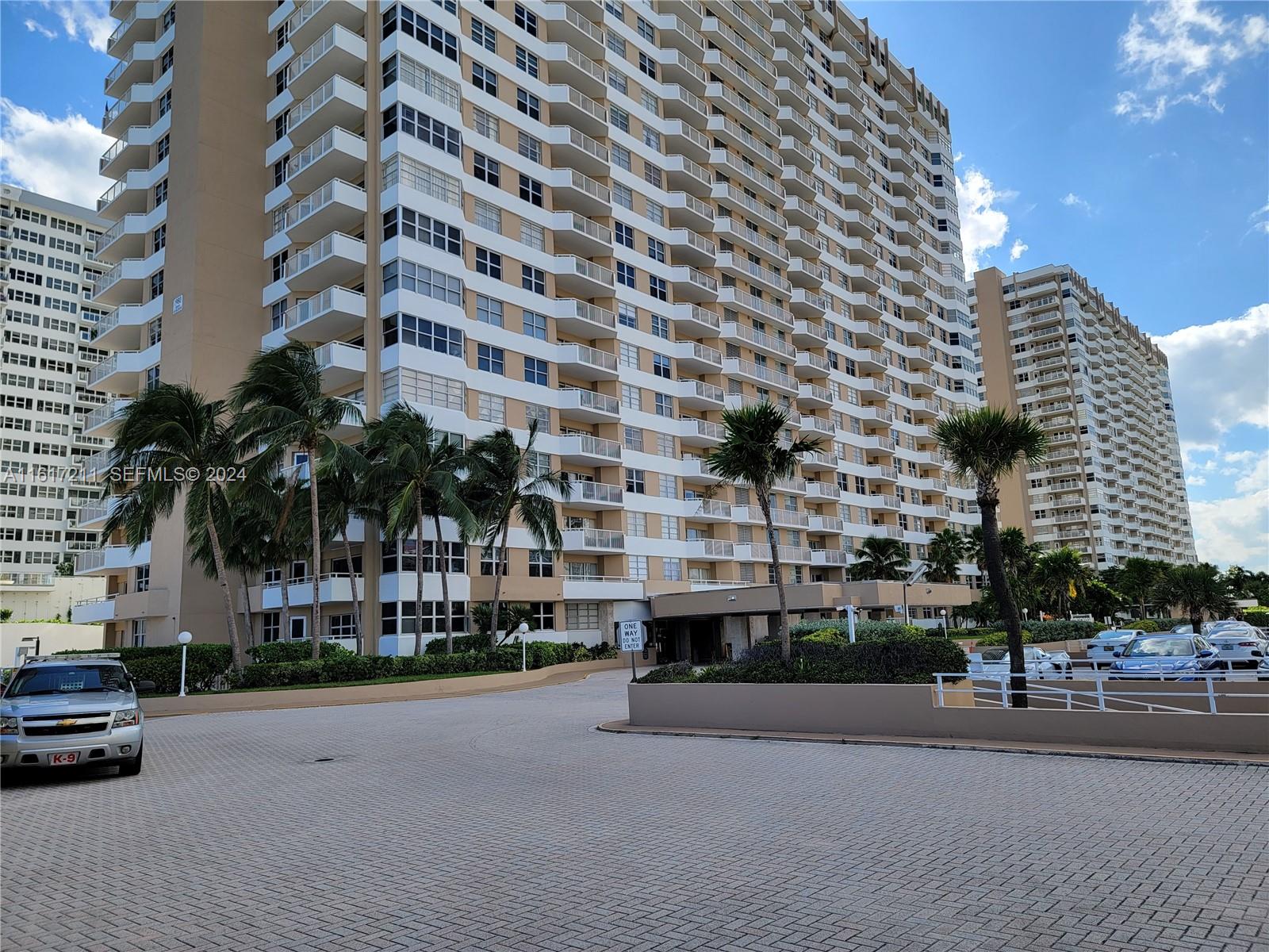 A paved driveway leads to the entrance of a large, multi-story residential apartment building — 1980 S Ocean Dr # 2C, Hallandale Beach FL 33009, HALLANDALE BEACH, FL