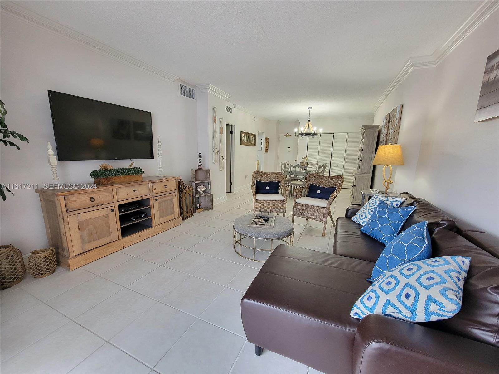 A living room features a brown sectional sofa, wicker chairs, and a wooden media console — 1980 S Ocean Dr # 2C, Hallandale Beach FL 33009, HALLANDALE BEACH, FL