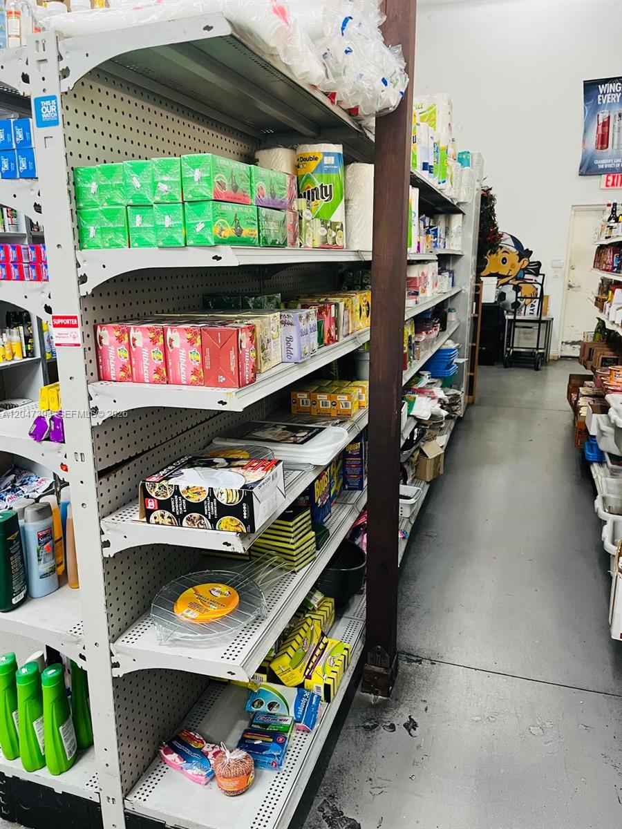 A narrow aisle in a retail store features shelves stocked with various food and household products — 222 NE 25th St, Miami FL 33137, MIAMI, FL