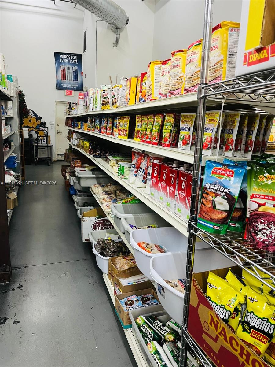 A narrow storage room features metal shelving units stocked with various packaged food products — 222 NE 25th St, Miami FL 33137, MIAMI, FL