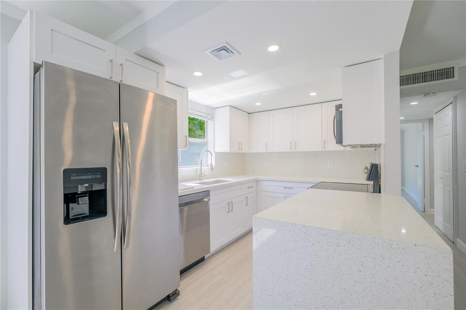 A modern kitchen features white cabinets, stainless steel appliances, and a white quartz countertop island — 633 Brittany # 633, Delray Beach FL 33446, DELRAY BEACH, FL