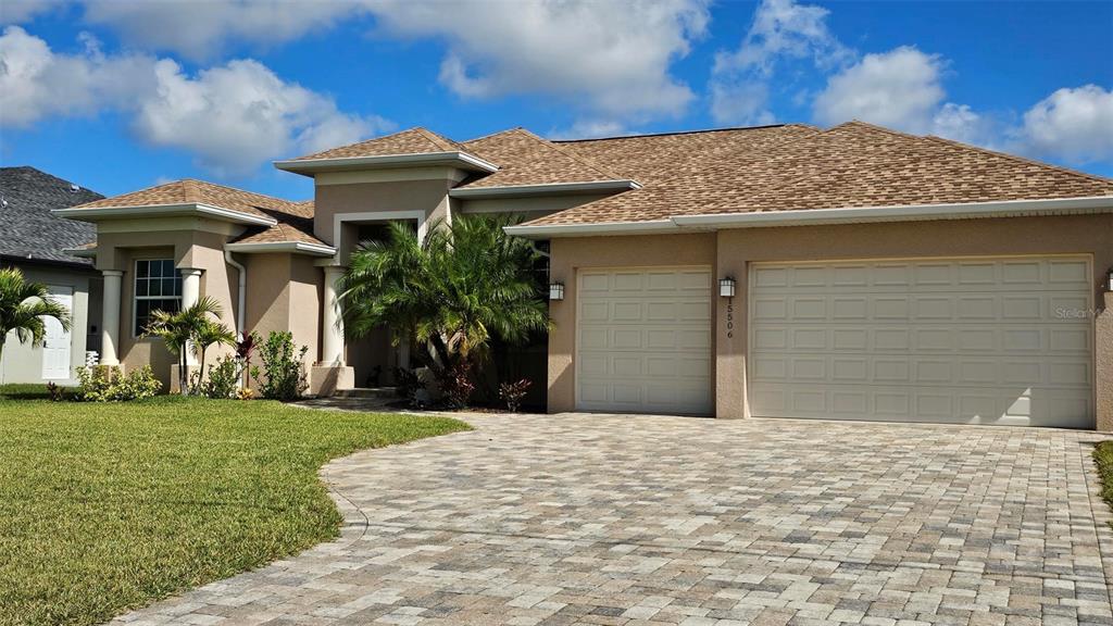 A single-story house with a beige stucco exterior, a shingled roof, and a paver driveway — 15506 MEACHAM CIRCLE, PORT CHARLOTTE, FL