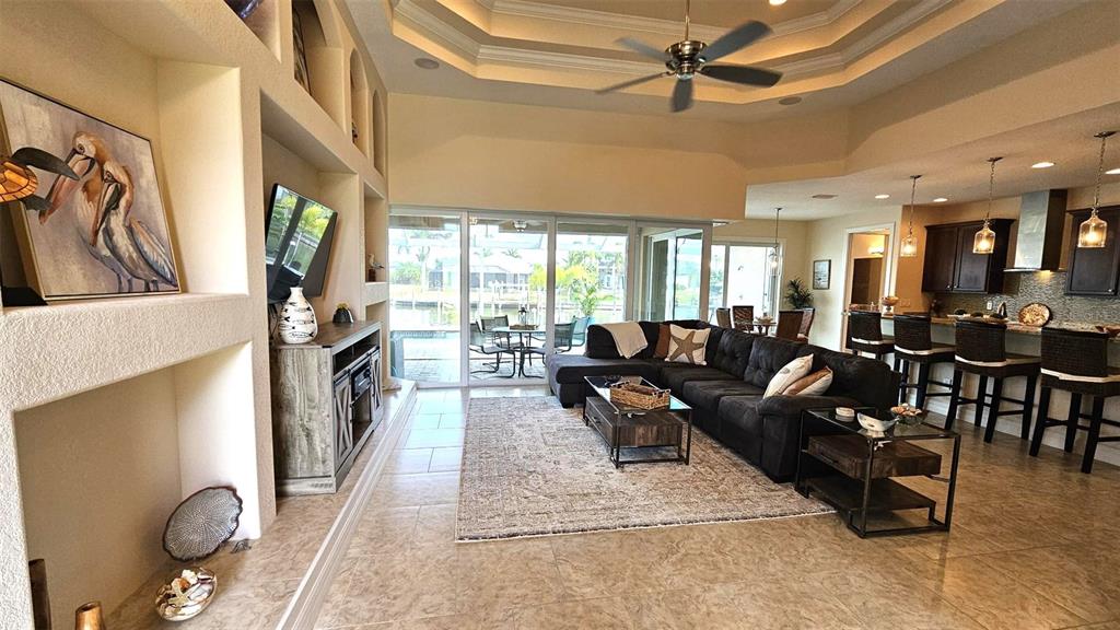 A spacious open-concept living room features a dark sectional sofa, tile flooring, and kitchen access — 15506 MEACHAM CIRCLE, PORT CHARLOTTE, FL