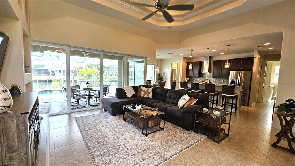 An open-concept living room and kitchen feature tile floors, a sectional sofa, and water views — 15506 MEACHAM CIRCLE, PORT CHARLOTTE, FL