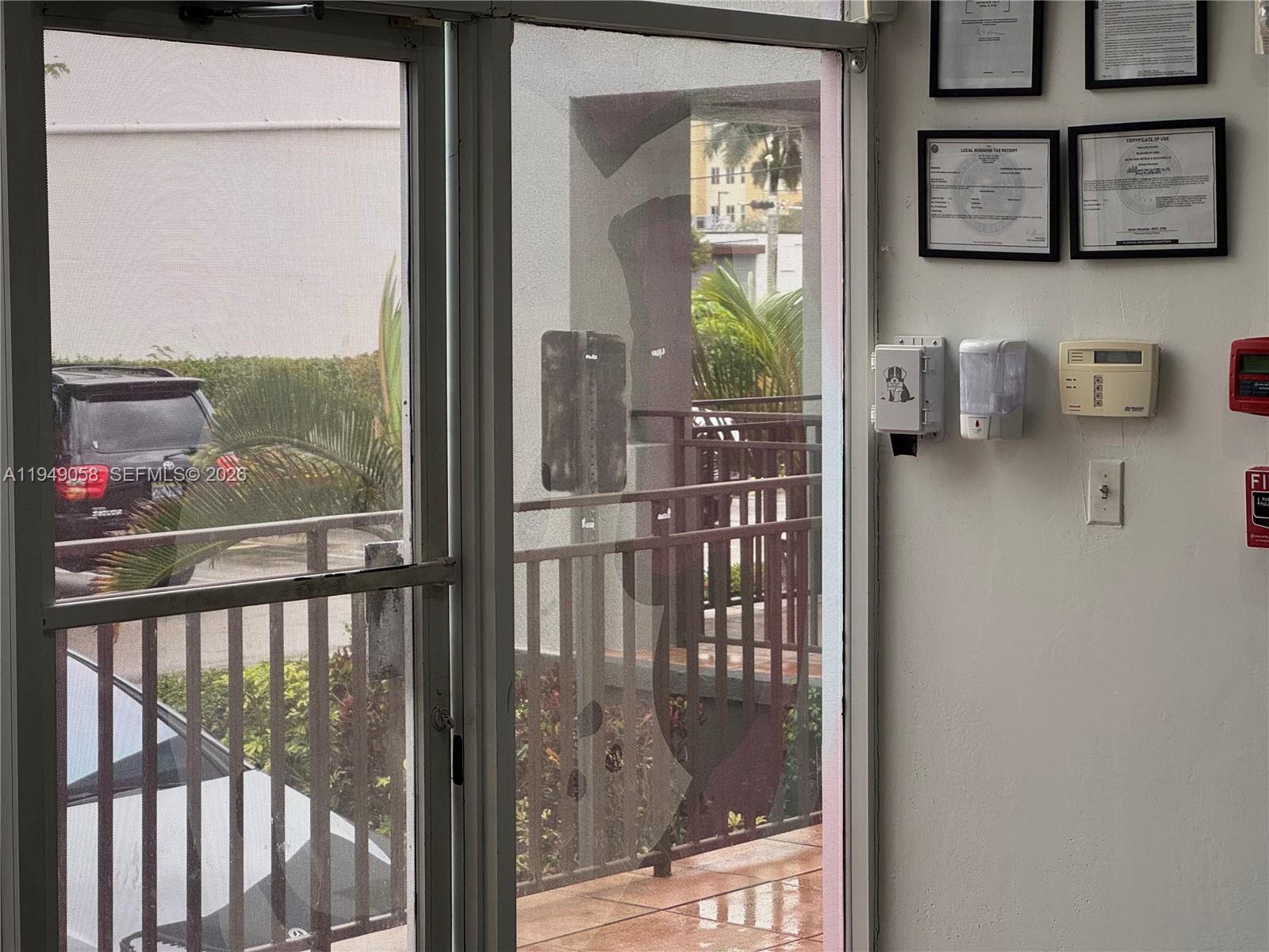 A view through a glass door shows a parking lot, palm trees, and railings — 8347 NW 36th St, Doral FL 33166, DORAL, FL