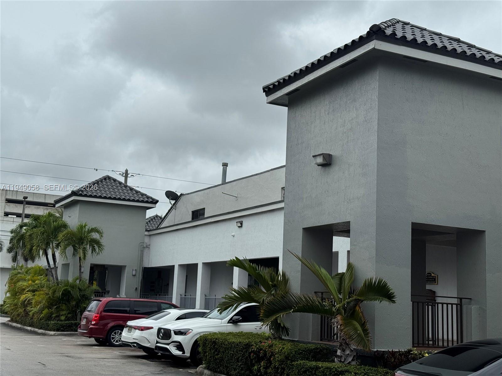 The exterior of a gray commercial building features a parking lot and palm trees — 8347 NW 36th St, Doral FL 33166, DORAL, FL