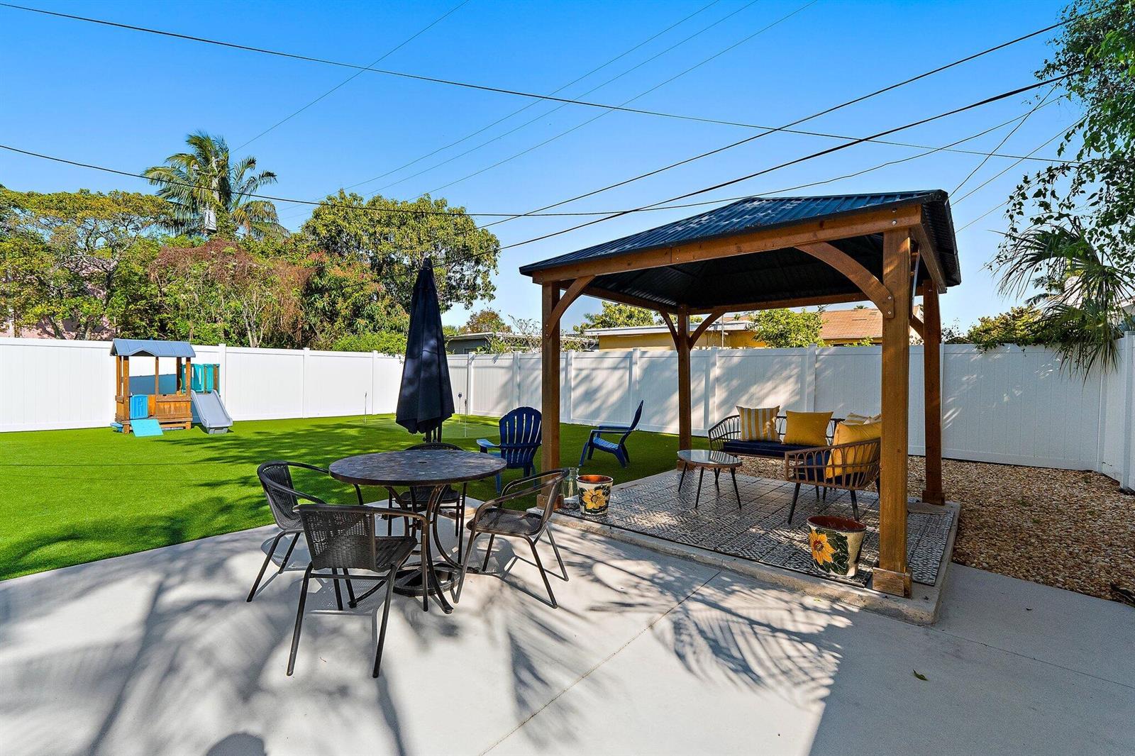 A backyard features a gazebo, a patio dining set, and a small playground on turf — 423 Avenida Alegre, West Palm Beach FL 33405, WEST PALM BEACH, FL