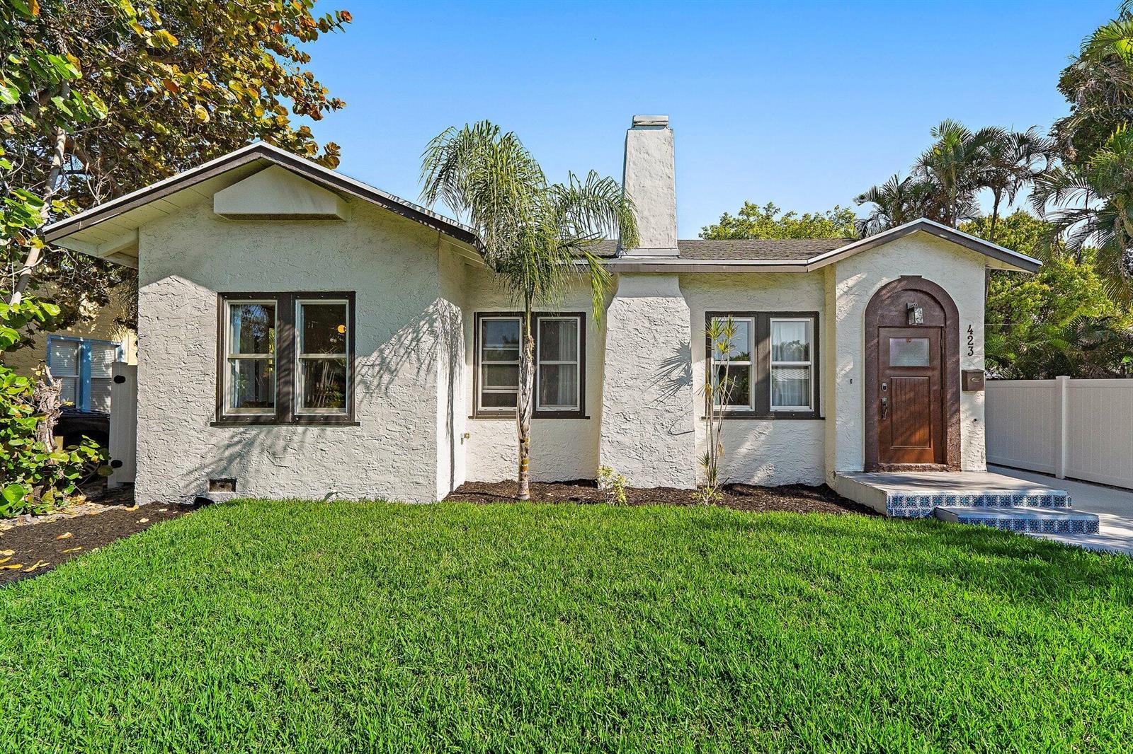 A single-story stucco house with a chimney, arched front door, and a front lawn — 423 Avenida Alegre, West Palm Beach FL 33405, WEST PALM BEACH, FL