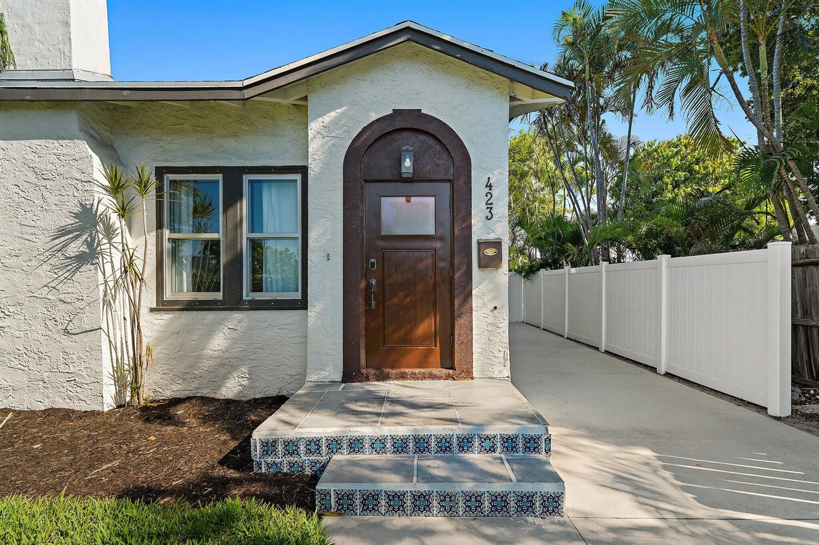 A white stucco house features an arched brown door and decorative tiled front steps — 423 Avenida Alegre, West Palm Beach FL 33405, WEST PALM BEACH, FL