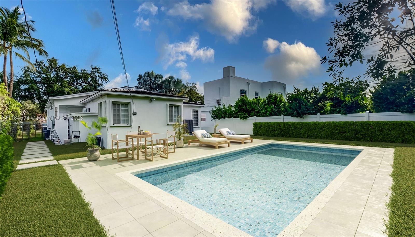 A backyard features a rectangular swimming pool, patio furniture, and a white house exterior — 535 W 51st St, Miami Beach FL 33140, MIAMI BEACH, FL