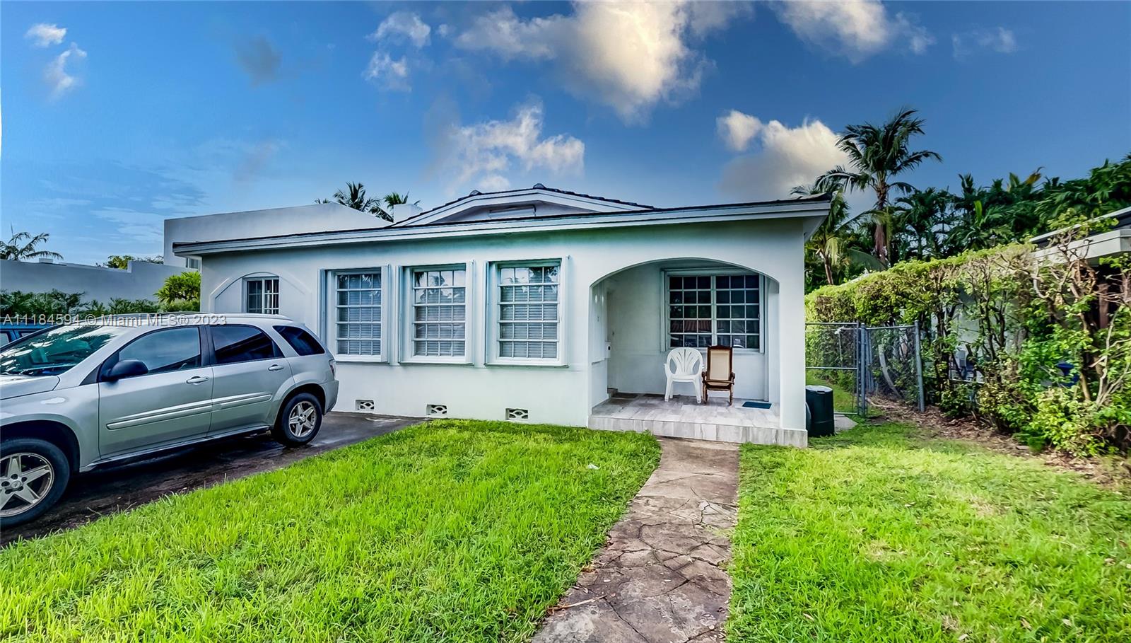 A single-story white house with a front porch, driveway, and lawn under a blue sky — 535 W 51st St, Miami Beach FL 33140, MIAMI BEACH, FL