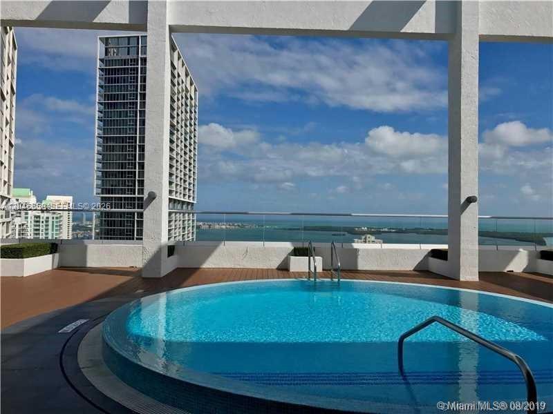 A circular rooftop swimming pool overlooks a bay and high-rise buildings under a blue sky — 500 Brickell Ave # 2006, Miami FL 33131, MIAMI, FL