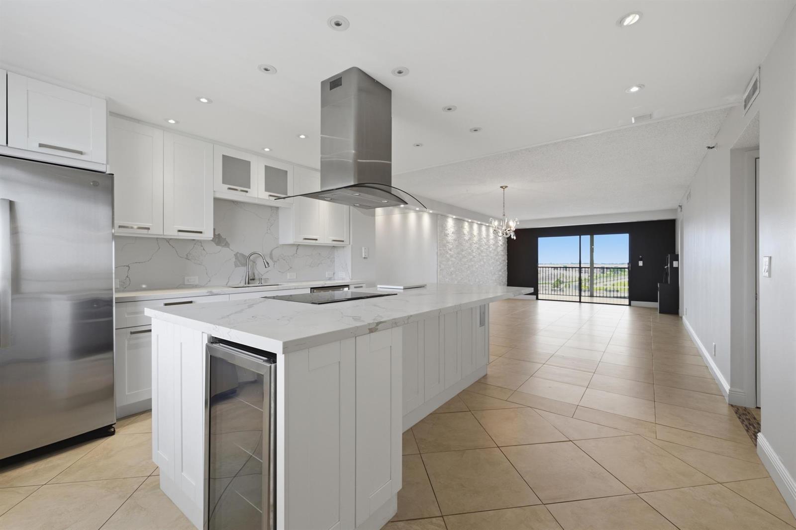 A modern kitchen features white cabinetry, marble countertops, a large island, and stainless steel appliances — 2215 Cypress Island Drive # 906, Pompano Beach FL 33069, POMPANO BEACH, FL