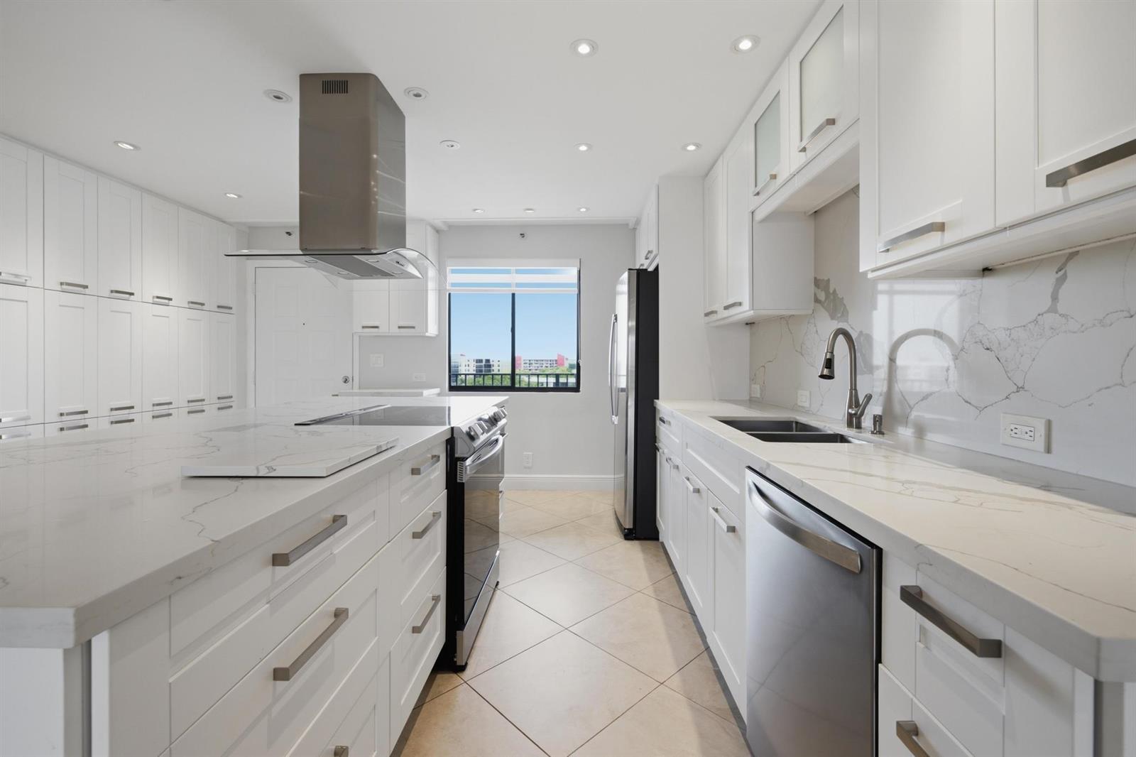 A modern kitchen features white cabinetry, marble-style countertops, stainless steel appliances, and a central island — 2215 Cypress Island Drive # 906, Pompano Beach FL 33069, POMPANO BEACH, FL