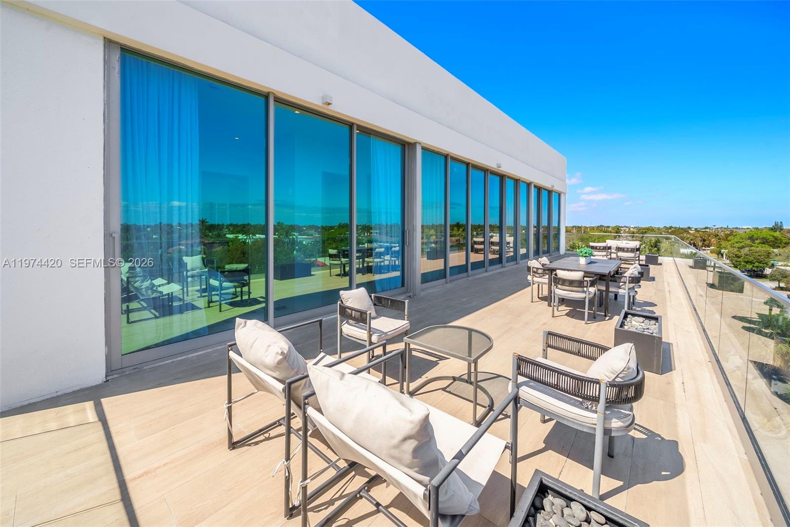 A spacious outdoor terrace features modern patio furniture, glass railings, and large floor-to-ceiling windows — 246 NE 6TH AVE PH, Delray Beach FL 33483, DELRAY BEACH, FL