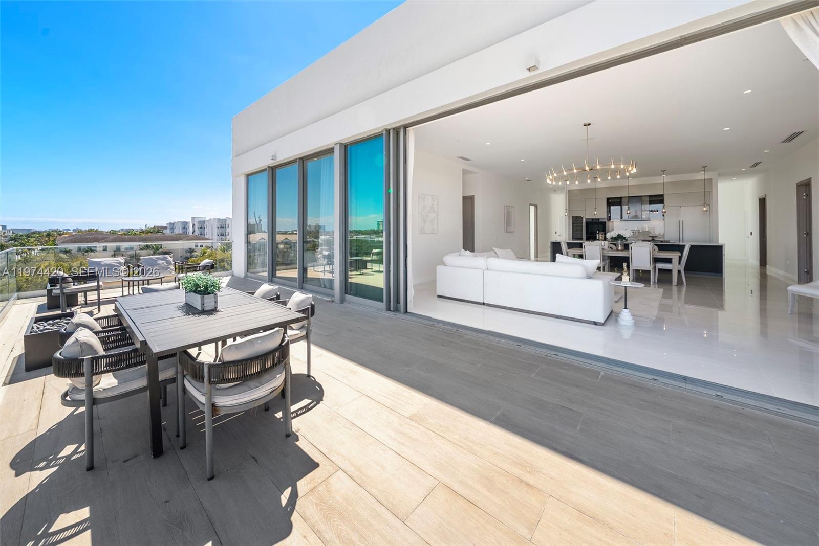 A modern apartment features a spacious balcony with outdoor dining and an open-concept interior — 246 NE 6TH AVE PH, Delray Beach FL 33483, DELRAY BEACH, FL