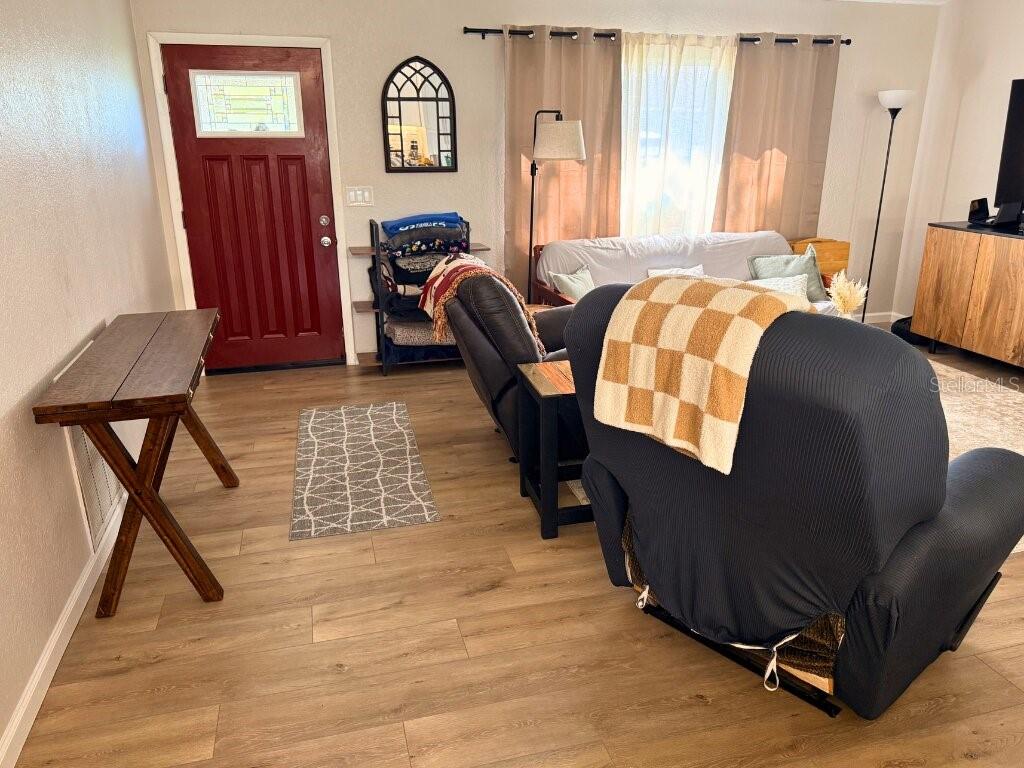 A kitchen features white cabinetry, granite countertops, stainless steel appliances, and light wood-look flooring — 7242 ASHMORE DRIVE, NEW PORT RICHEY, FL
