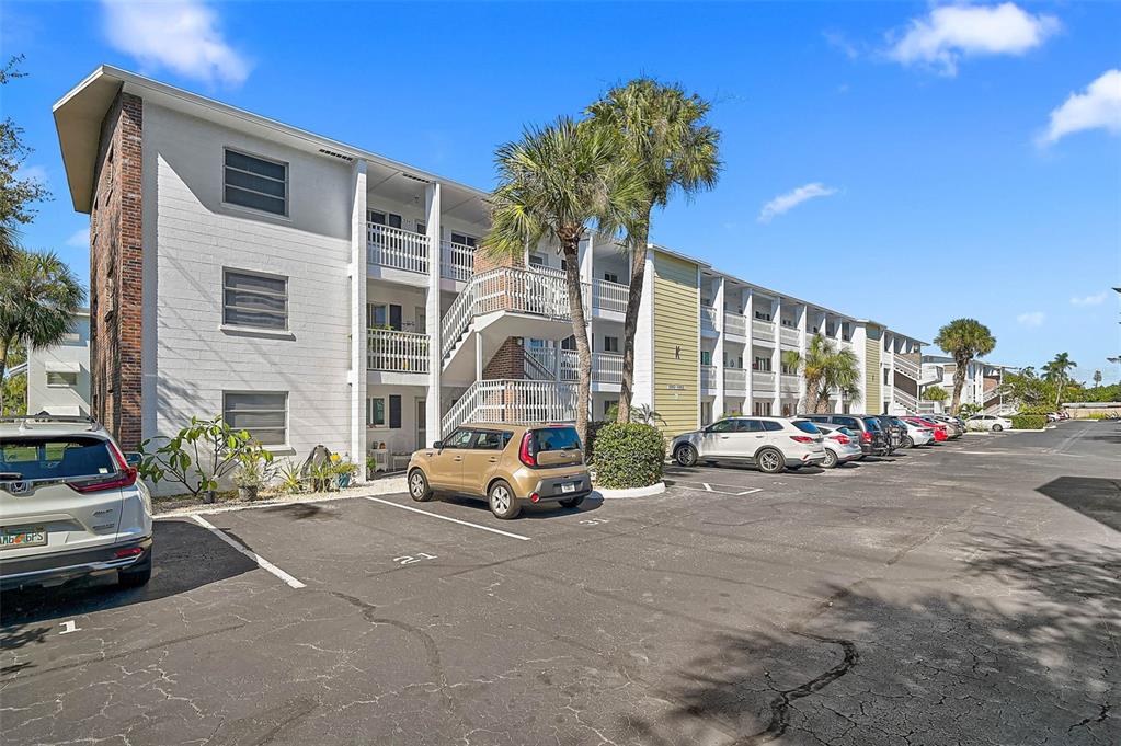 A multi-story apartment building features white siding, exterior staircases, and a parking lot in front — 5940 EASY STREET UNIT K31, BRADENTON, FL