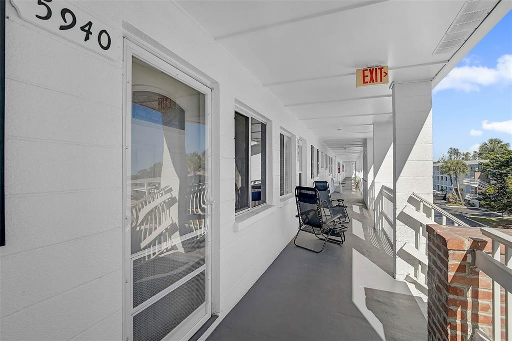 An exterior walkway features white walls, a screen door, and two folding chairs — 5940 EASY STREET UNIT K31, BRADENTON, FL
