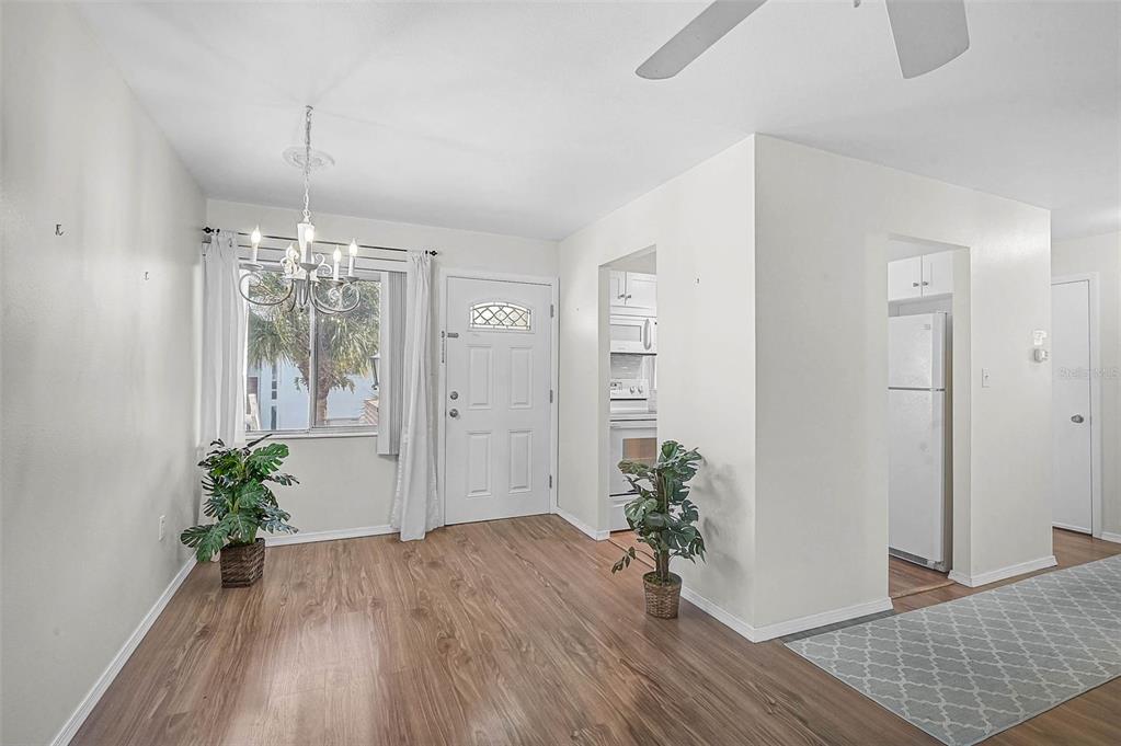 A dining area with wood-look flooring, a white front door, and an adjacent kitchen — 5940 EASY STREET UNIT K31, BRADENTON, FL
