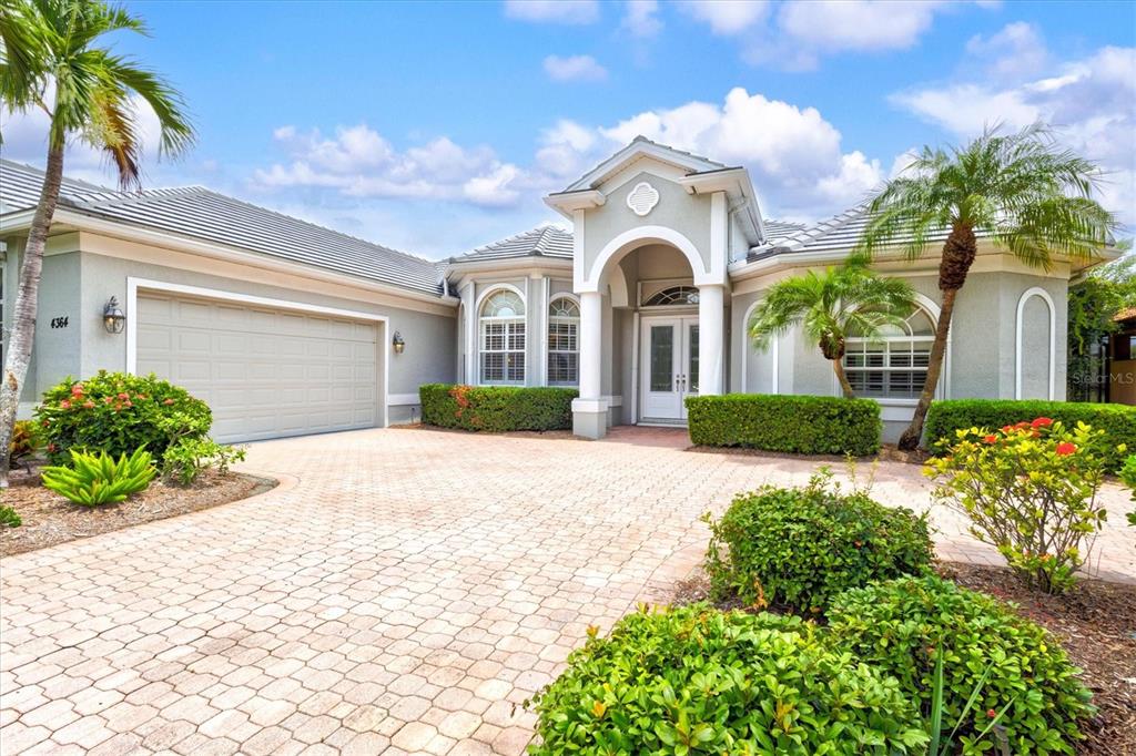 A single-story house with a paved driveway, a two-car garage, and a covered entryway — 4364 CORSO VENETIA BOULEVARD, VENICE, FL