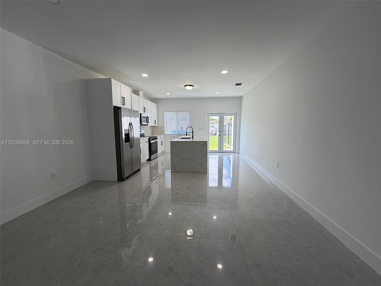 A modern kitchen features white cabinetry, stainless steel appliances, a marble-patterned island, and tiled floors — 12080 & 12090 SW 213th St, Miami FL 33177, MIAMI, FL