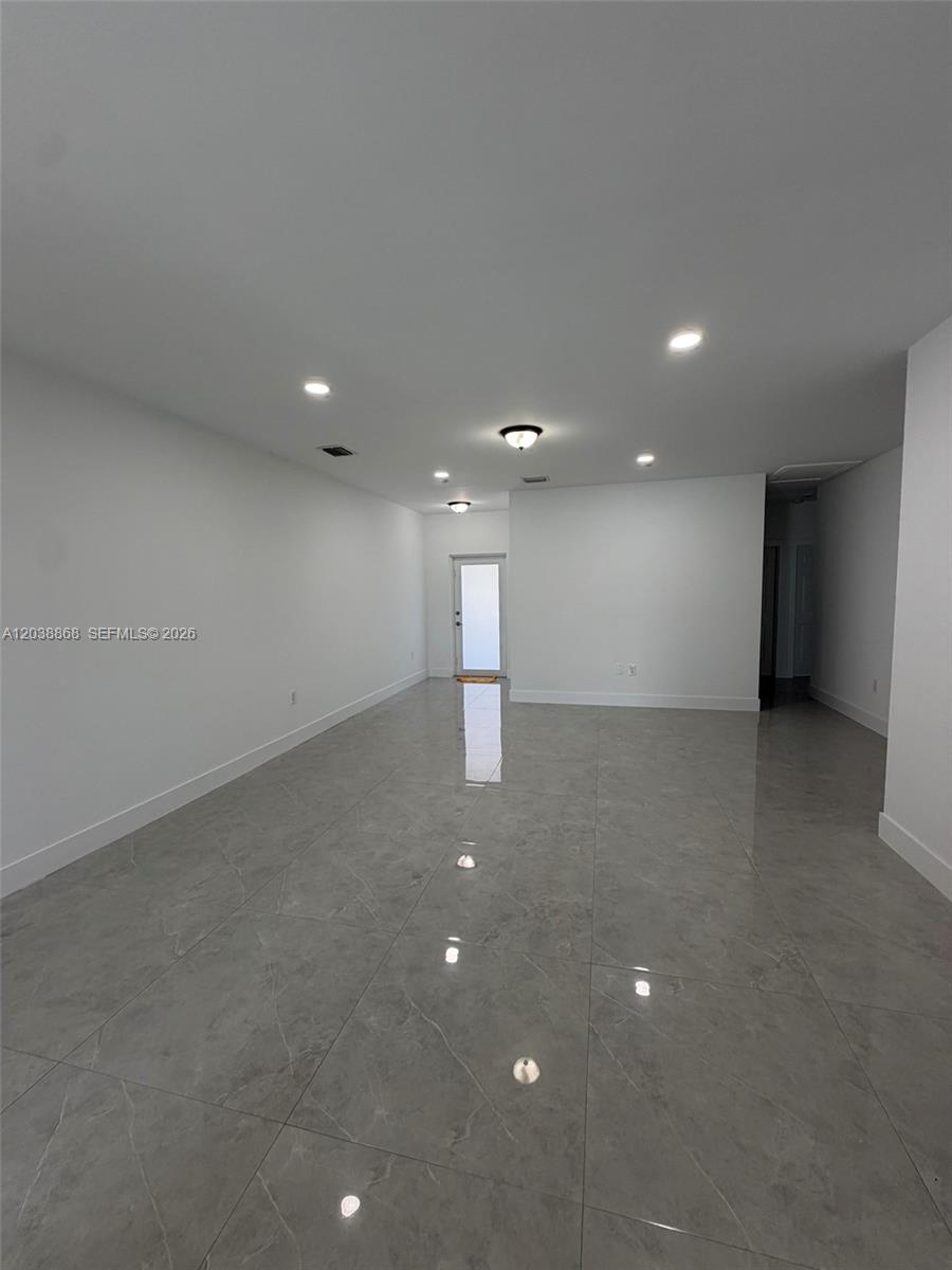 An empty room features white walls, recessed lighting, and large gray marble-look floor tiles — 12080 & 12090 SW 213th St, Miami FL 33177, MIAMI, FL