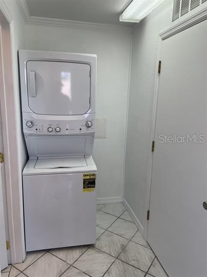 A white stacked washer and dryer unit sits in a small laundry room with tiled floors — 15 S DOLLINS AVENUE, ORLANDO, FL