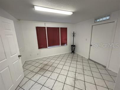 A room with white walls, white tiled floors, a window with red blinds, and a door — 15 S DOLLINS AVENUE, ORLANDO, FL