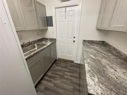 A laundry room features grey cabinets, a stainless steel sink, and granite countertops — 15 S DOLLINS AVENUE, ORLANDO, FL