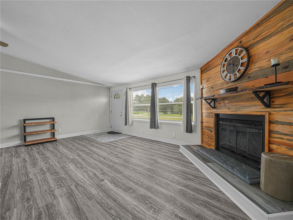 A living room features wood-look flooring, a fireplace with a wood-plank wall, and large windows — 3559 REAGAN BOULEVARD, LAKE WALES, FL