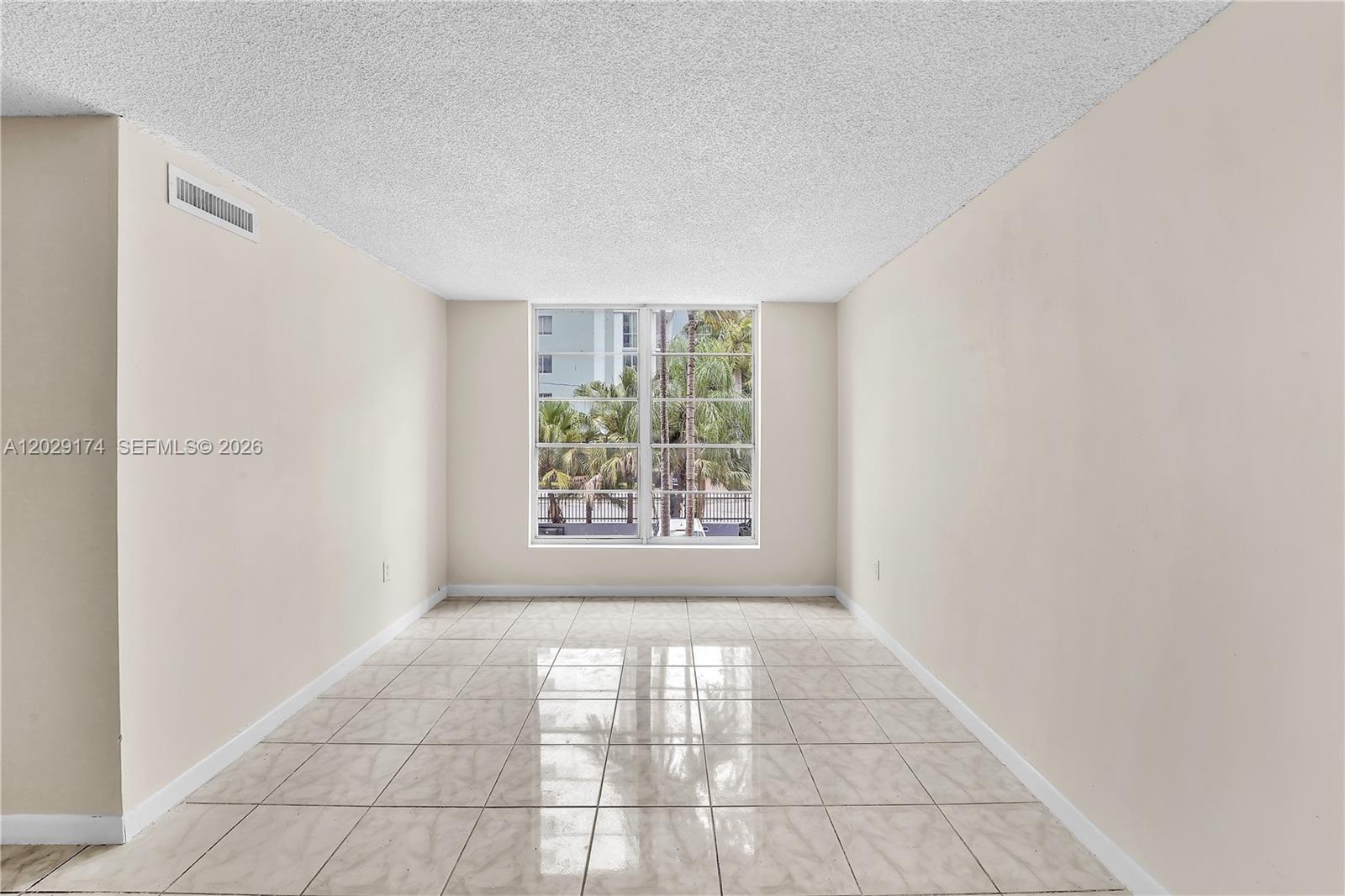 An empty room features beige walls, light-colored tile flooring, a popcorn ceiling, and a window — 210 SW 11th St # 209, Miami FL 33130, MIAMI, FL