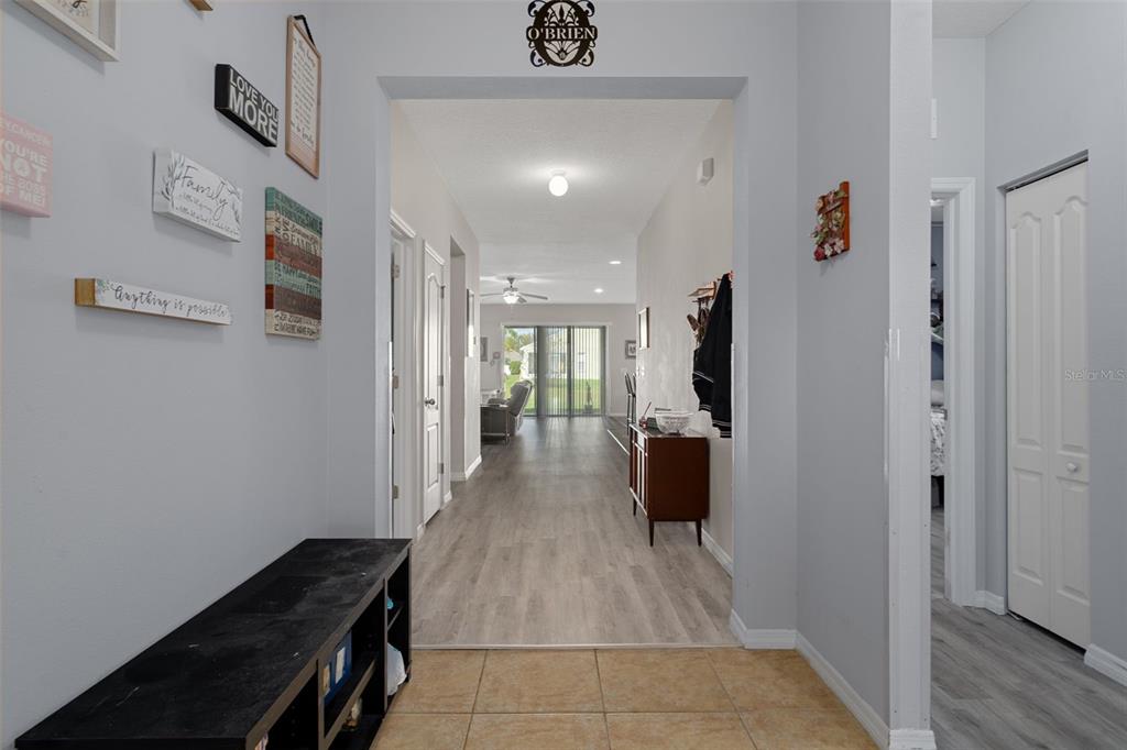 A tiled entryway leads into a hallway with wood-look flooring and a view of a living area — 36154 LAGUNA HILLS CIRCLE, ZEPHYRHILLS, FL