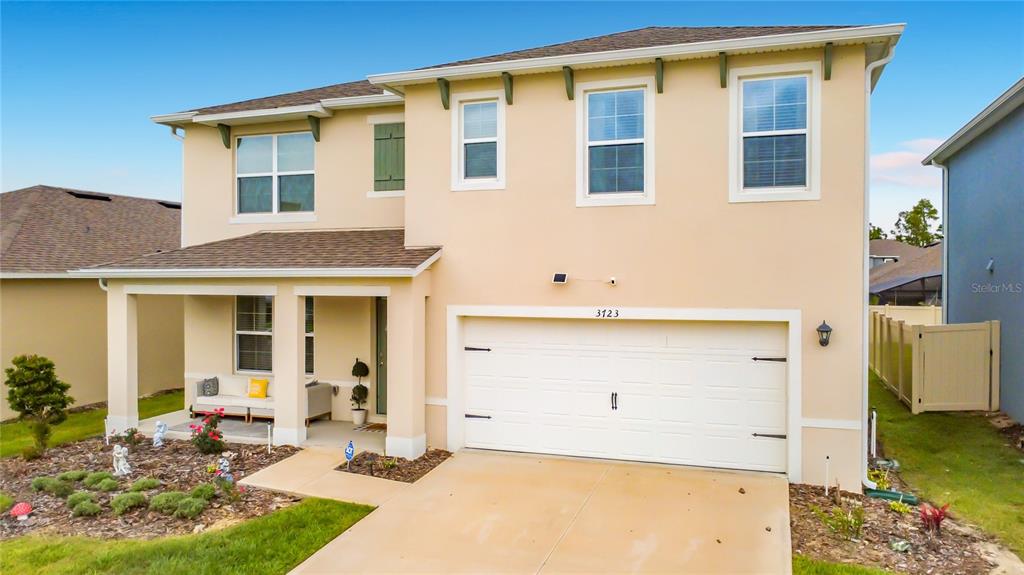 A two-story suburban house features a beige stucco exterior, a two-car garage, and a porch — 3723 PARAGON LANE, CLERMONT, FL