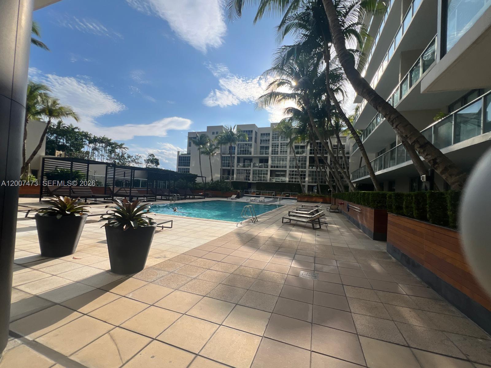 An outdoor swimming pool area features lounge chairs, potted plants, and palm trees — 3470 E Coast Ave # H0501, Miami FL 33137, MIAMI, FL