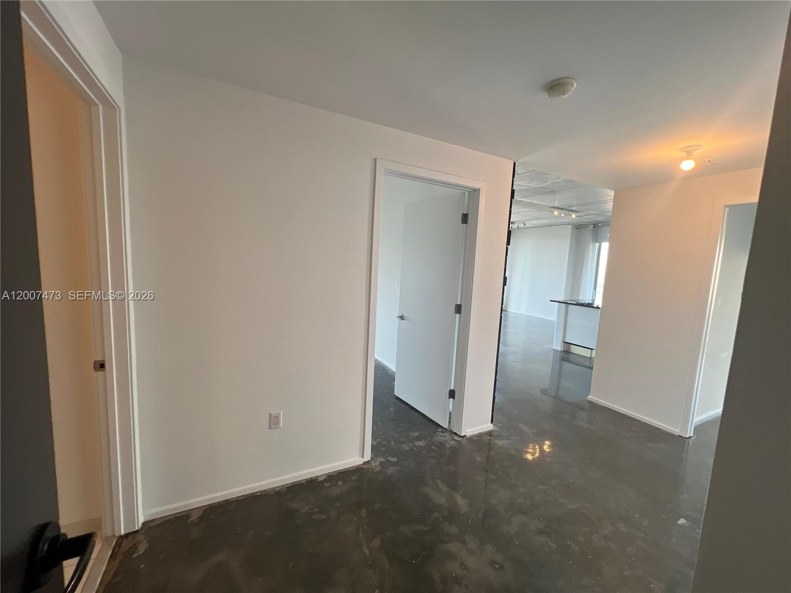 An interior view shows a hallway with white walls, gray concrete floors, and doorways — 3470 E Coast Ave # H0501, Miami FL 33137, MIAMI, FL