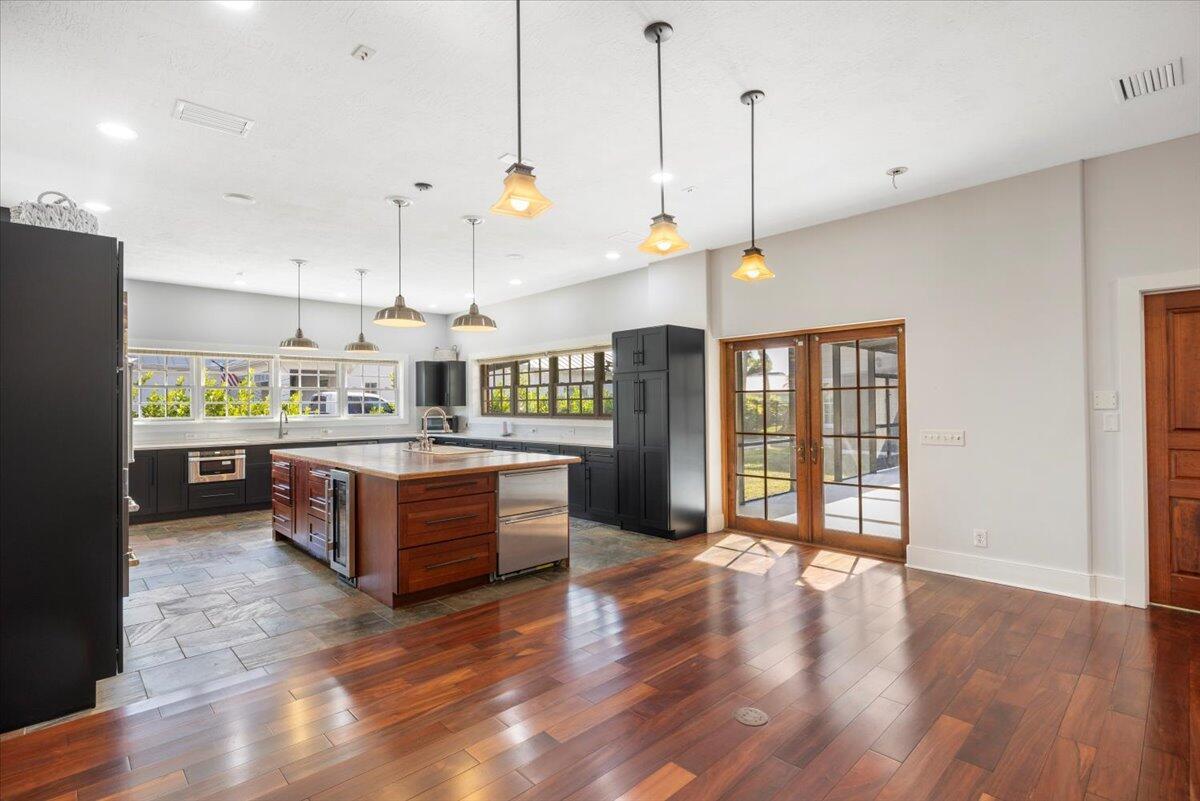 A kitchen features dark cabinetry, a wood-topped island, and hardwood floors next to glass doors — 531 Sunset Boulevard, Melbourne Beach FL 32951, MELBOURNE BEACH, FL