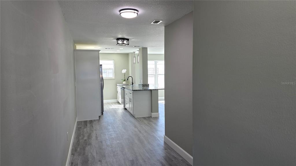 A view from a hallway looking into a kitchen with white cabinets and gray flooring — 5623 80TH ST N UNIT 510, ST PETERSBURG, FL