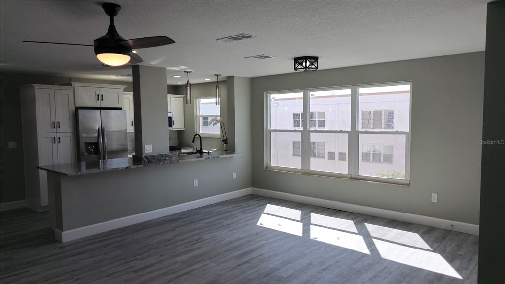 A kitchen with white cabinets and a breakfast bar opens into a living area — 5623 80TH ST N UNIT 510, ST PETERSBURG, FL