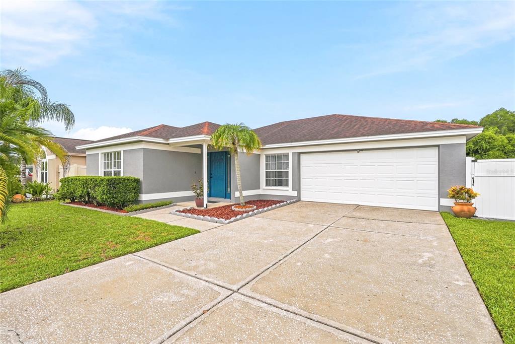 A single-story house with a gray exterior, a two-car garage, and a blue front door — 11026 STREAMSIDE DRIVE, TAMPA, FL
