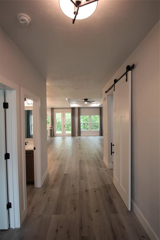 A hallway with light wood-look flooring leads to an open living area with French doors — 4102 NW 26TH DRIVE, GAINESVILLE, FL