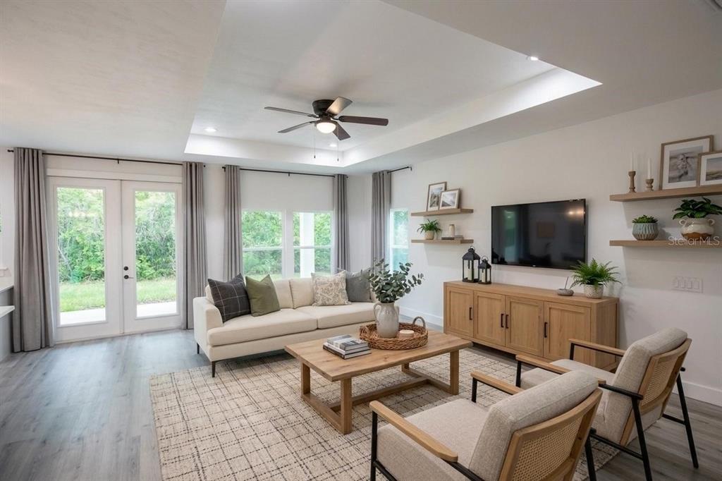 A living room with a tray ceiling, light wood furniture, and a neutral-toned area rug — 4102 NW 26TH DRIVE, GAINESVILLE, FL