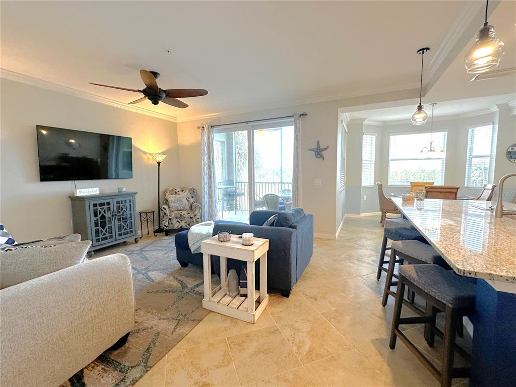 An open-concept living room and kitchen area with tile floors, a ceiling fan, and balcony — 14081 HERITAGE LANDING BOULEVARD UNIT 223, PUNTA GORDA, FL