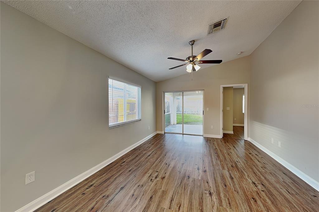 A living room with wood-look flooring, a ceiling fan, and sliding glass doors to a patio — 530 SCARLET MAPLE COURT, PLANT CITY, FL