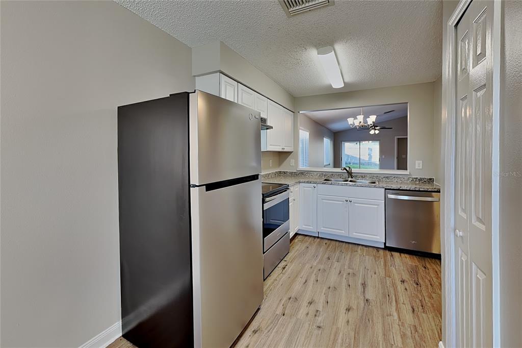 A kitchen features stainless steel appliances, white cabinets, and light wood-look flooring — 530 SCARLET MAPLE COURT, PLANT CITY, FL