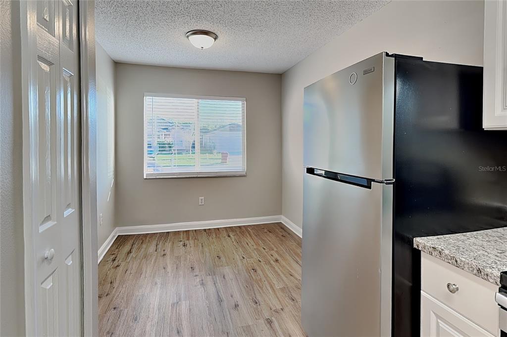 A kitchen dining area features wood-look flooring, a window with blinds, and a stainless refrigerator — 530 SCARLET MAPLE COURT, PLANT CITY, FL