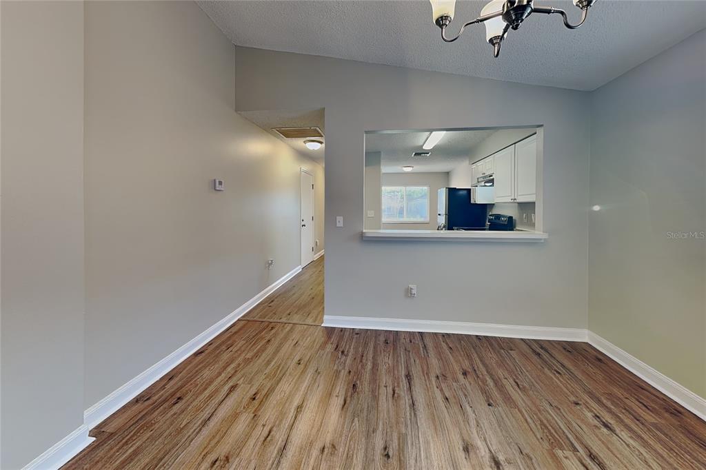 A dining area with wood-look flooring features a pass-through window looking into the kitchen — 530 SCARLET MAPLE COURT, PLANT CITY, FL