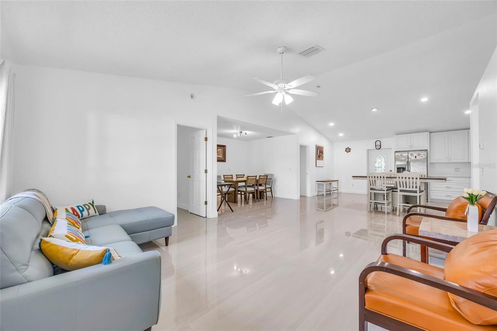 A bright, open-concept living and dining area features white walls, tile flooring, and modern furniture — 4211 FLOATING ORCHID COURT, ST CLOUD, FL