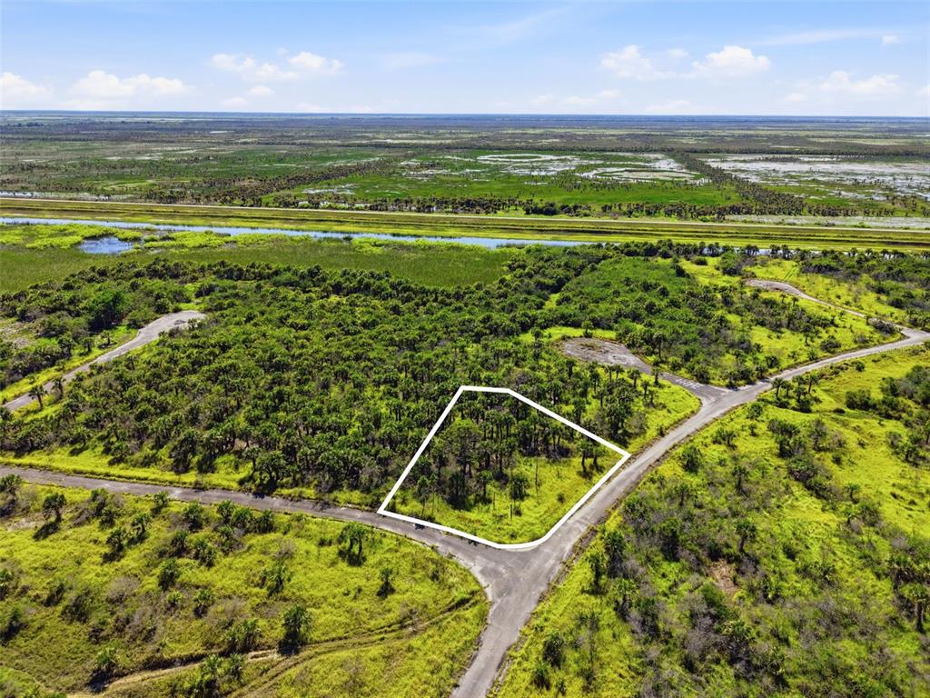 An aerial view shows a vacant, wooded lot outlined in white at a road intersection — NO ADDRESS, PALM BAY, FL