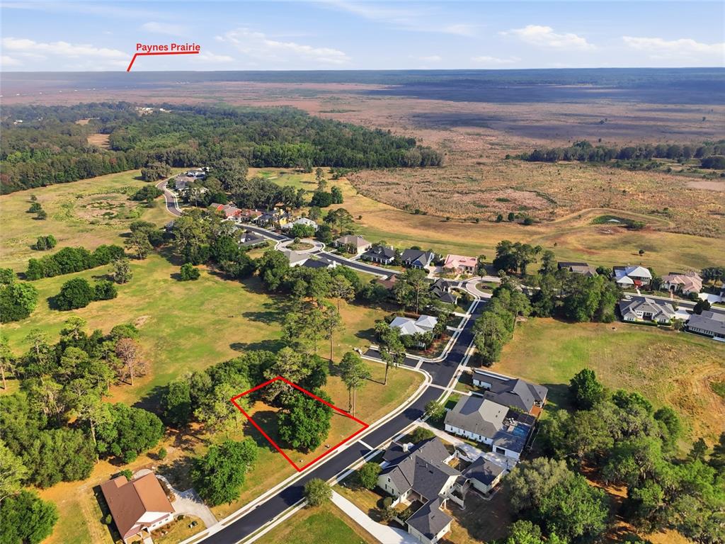 An aerial view shows a vacant, tree-covered residential lot outlined in red near a prairie — 6713 SW 40TH TERRACE, GAINESVILLE, FL